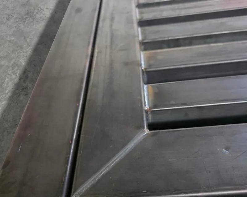 Close-up of a clean laser-welded corner joint on a slatted steel panel